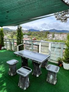a picnic table and two stools on a balcony at Sameer Mountain View Glamping in Cameron Highlands