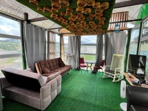 a living room with a couch and a table and windows at Sameer Mountain View Glamping in Cameron Highlands