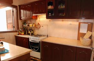 La cuisine est équipée de placards en bois et d'un four avec plaques de cuisson. dans l'établissement Private Holiday Apartment, à Tarrafal