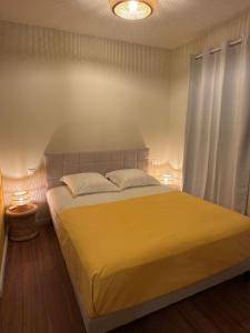 a bedroom with a large bed with a yellow blanket at Villa Cap Jaune - 30min Volcan - Rando et Confort 4 étoiles in Saint-Joseph +21 photos
