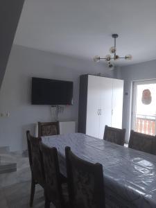 a dining room with a table and chairs and a television at Maia's Cottage in Bakuriani