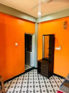 an orange room with a dresser and a mirror at Shan guest rooms in Jaffna