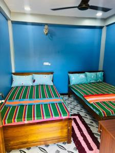 two beds in a room with blue walls at Shan guest rooms in Jaffna