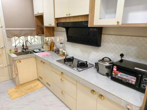 a kitchen with a stove and a microwave at Serai Homestay in Dungun