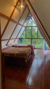 two beds in a room with a large window at Cabañas Metztonalli in Xilitla