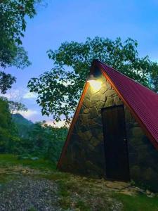 a stone building with a red roof with a door at Cabañas Metztonalli in Xilitla