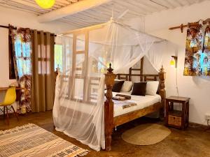 a bedroom with a canopy bed with white drapes at Casa Hera Diani in Diani Beach