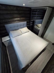ein großes weißes Bett in einem Zimmer mit einem Spiegel in der Unterkunft Vaaranpää in Kotaniemi