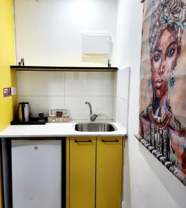 a kitchen with a sink and a painting of a woman at Amdar boutique in Eilat