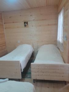 two beds in a room with wooden walls at Riverside Nature in Martvili