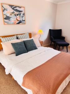 a bedroom with a large bed and a black chair at Esperance Seaside Cottage in Esperance