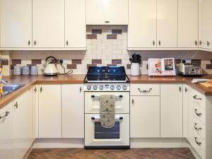 a kitchen with a stove and white cabinets at Corbetts Lodge Cottage in Swaffham