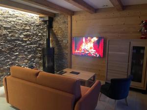 a living room with a couch and a tv on a wall at Chalets Coeur du Lac in Malbuisson