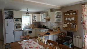 a kitchen with a table and a white refrigerator at DOM NAD JEZIOREM KUŹNIa in Łąkie
