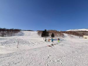 a group of people standing on a snow covered slope at 苗場ウッドインだいまる in Yuzawa