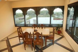 a dining room with a table and chairs and windows at The Gold Mount Villa in Udaipur