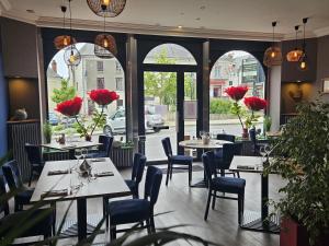 a restaurant with tables and chairs and red flowers at Logis Loire Hotel - Les Cocottes Restaurant in Les Rosiers