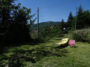 różowe krzesło siedzące w trawie obok ławki w obiekcie Ca Du Ventu w mieście Carbuta