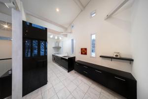 a large kitchen with black cabinets and a sink at Powdersuites in Hakuba +43 photos