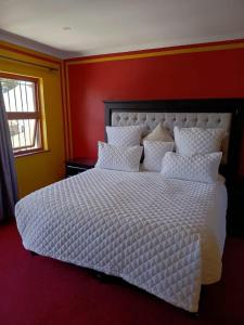 a bedroom with a white bed with a red wall at Capetown Adilo Villa 2 in Cape Town +6 photos