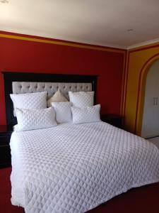 a bedroom with a white bed with a red wall at Capetown Adilo Villa 2 in Cape Town