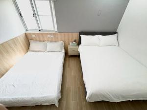 two beds in a small room with white sheets at Happiness B&B in Linbian