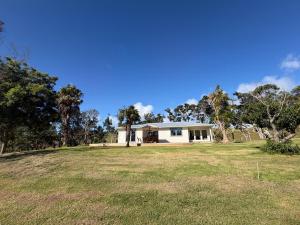 a house with a large grassy field in front of it at Pouto Farms Packhouse - Coastal Farmhouse in Pouto