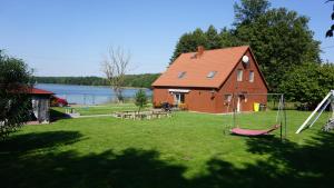 a yard with a house and a swing at DOM NAD JEZIOREM KUŹNIa in Łąkie