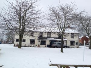 un edificio en la nieve con árboles delante en The Swan at Great Kimble en Aylesbury