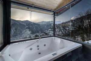 a bath tub in a room with a large window at Echor Himalayan Sky Cabins Sethan, Manali in Manāli