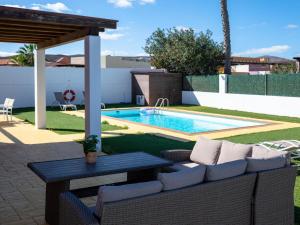 a patio with a couch and a table and a pool at Villa Solara in Caleta De Fuste