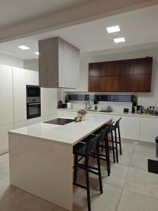 a kitchen with a large white island with bar stools at Maximos Luxury Villa Monagri Limassol in Monagri