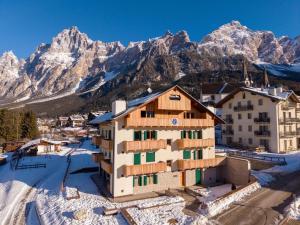 a building in the snow with mountains in the background at Arga' New Alpine Design Apartment Central & Scenic Views in San Vito di Cadore