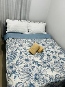 a bed with a blue and white comforter with two towels on it at Casa Residence by Baluyut in Concepcion