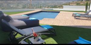 a pool with a chair and a bottle of wine next to it at Maximos Luxury Villa Monagri Limassol in Monagri