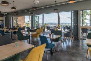 a restaurant with tables and chairs and large windows at Apartamenty Niegocin in Wilkasy