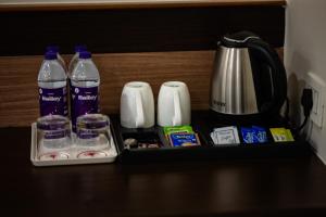 a tray with water bottles and cups and a coffee maker at Hotel Gharana Tree in Gaya