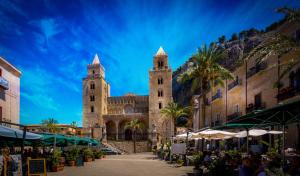 a church with two towers with palm trees in front at Porto Salvo Apartments - by Vacation Service in Cefalù