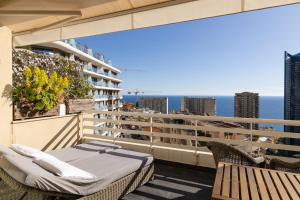 a balcony with a bed and chairs and the ocean at Beausoleil near Monaco - Cosy Studio with Sea view in Beausoleil