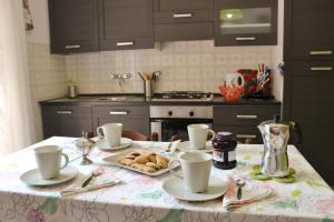 una cocina con una mesa con tazas y galletas. en Casa Mattia by Holiday World, en Bellano