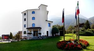 a white building with some flowers in the grass at Hotel Diana Jardin et Spa in Aosta