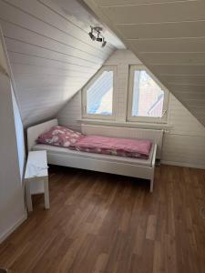 ein kleines Bett in einem Zimmer mit zwei Fenstern in der Unterkunft Dachstudio Eggingen in Eggingen