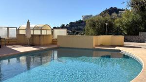 a large swimming pool with blue water in a yard at Beausoleil near Monaco - Cosy Studio with Sea view in Beausoleil