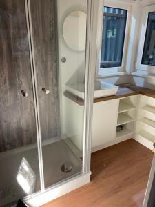 a bathroom with a glass shower with a sink at Tiny House Moritz in Fedderwardersiel