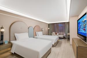 a hotel room with two beds and a flat screen tv at Mercure Beijing Anzhen Olympic Center in Beijing