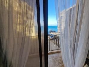 Meerblick von einem Balkon mit weißen Vorhängen in der Unterkunft Oyster 2 Beachfront bliss in Qbajjar
