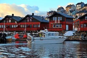 a white boat in the water in front of houses at Havøysund Hotell & Rorbuer in Havøysund