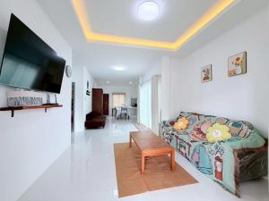 a living room with a couch and a flat screen tv at Ban Belife14 in Ban Tha Chin (1)