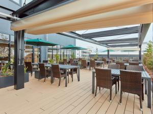 an outdoor patio with tables and chairs and umbrellas at Hotel Terrasta in Miyakonojō