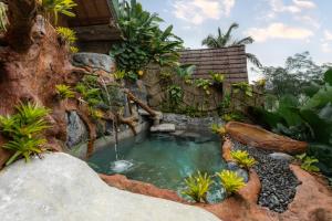 a small pond with a waterfall in a garden at Vana Nugraha Villas in Tampaksiring